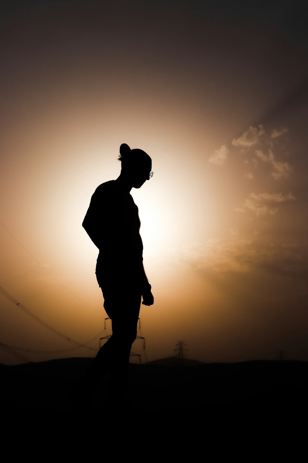 silhouette of man standing on hill during sunset