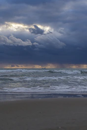 Dark storm clouds gather over the Nevis coastline, waves crashing violently against stone colonial buildings.