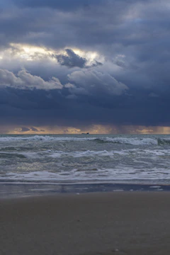 Dark storm clouds gather over the Nevis coastline, waves crashing violently against stone colonial buildings.