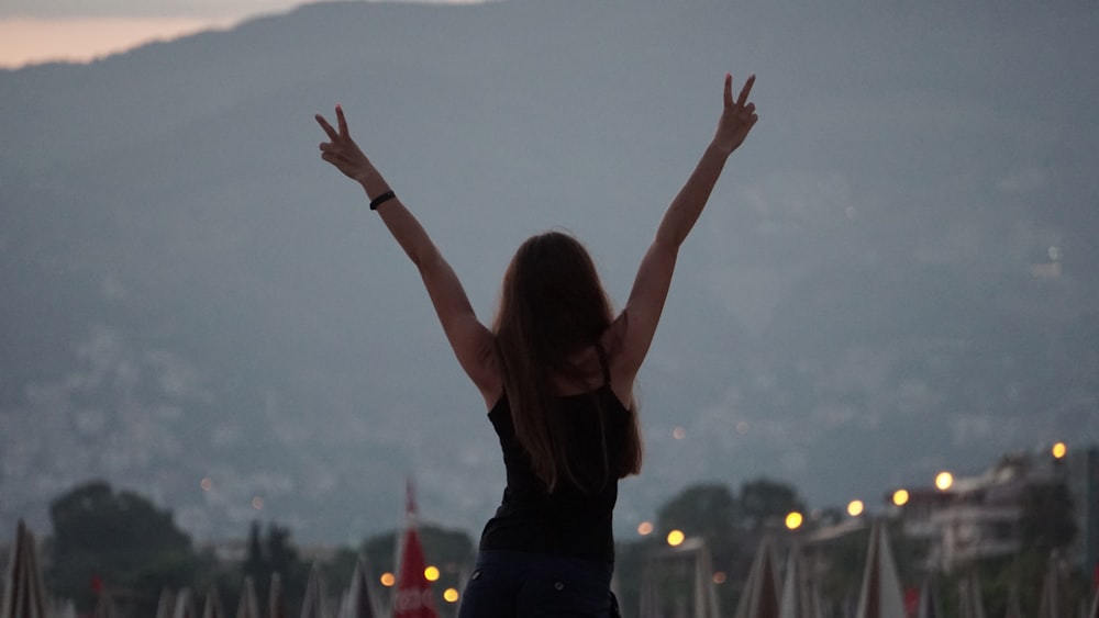 woman in black tank top raising her hands