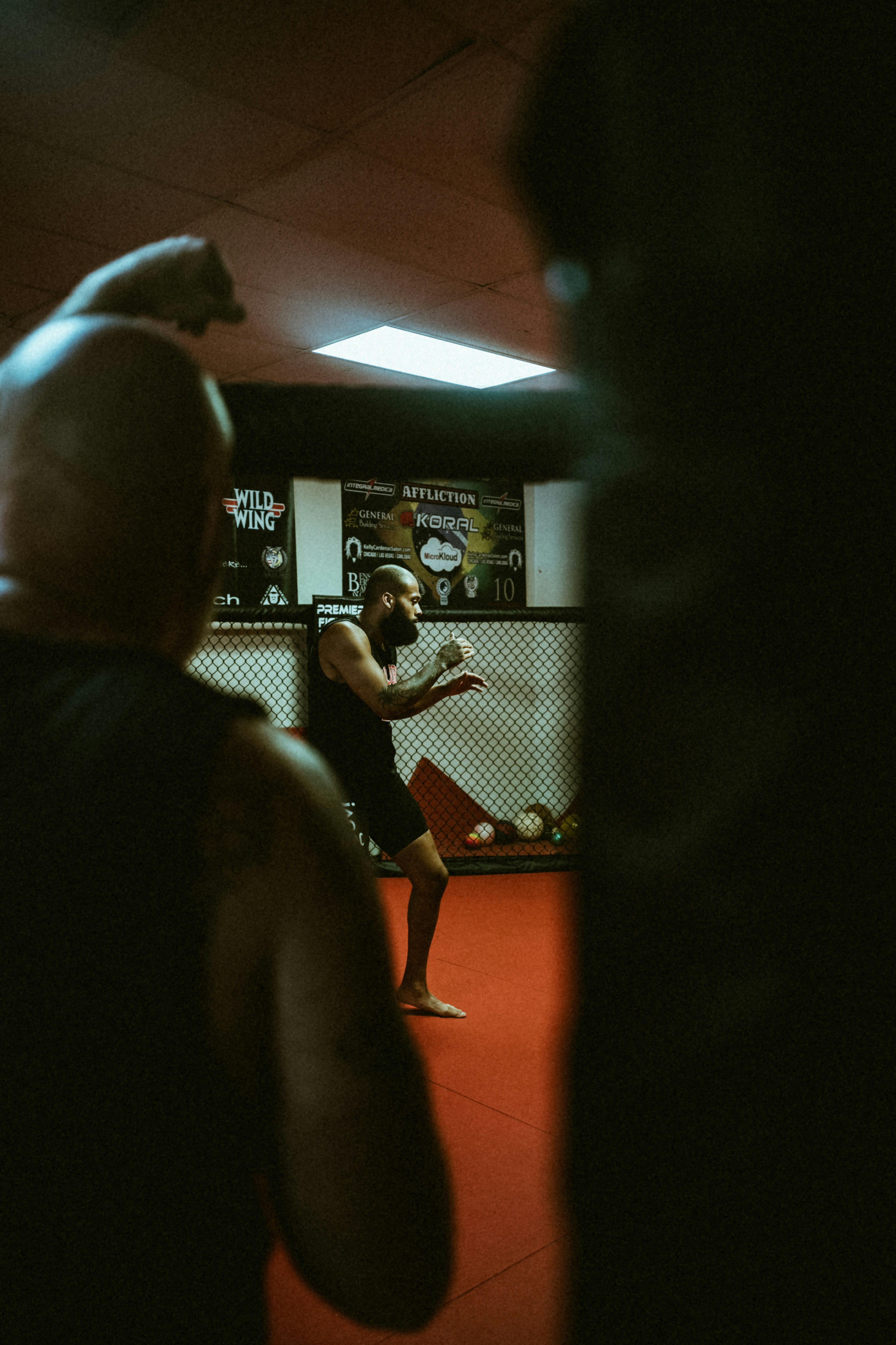 MMA fighter in cage training stance with gloves, intense gym lighting