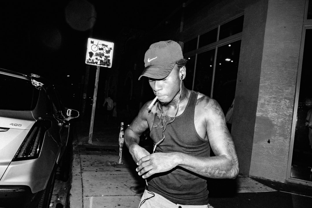 man in tank top and cap sitting on wooden floor