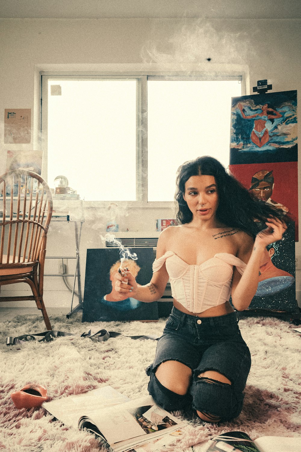 woman in white brassiere and black denim shorts sitting on brown wooden chair