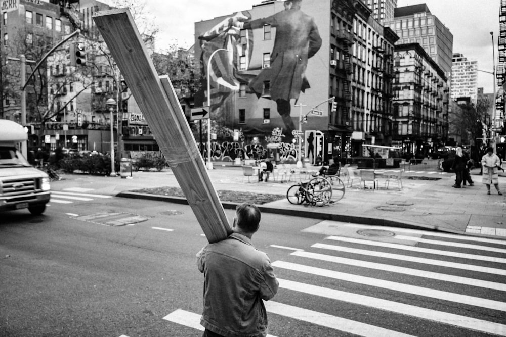 grayscale photo of man in t-shirt standing on pedestrian line