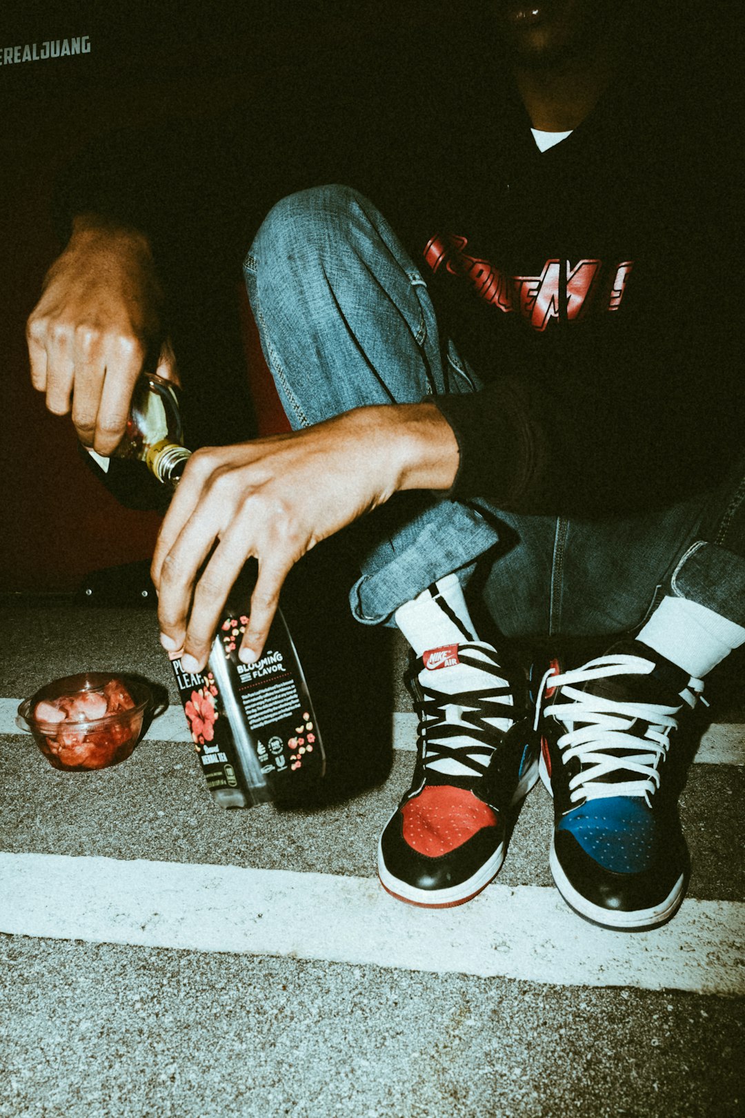 person in blue denim jeans holding black and white labeled bottle