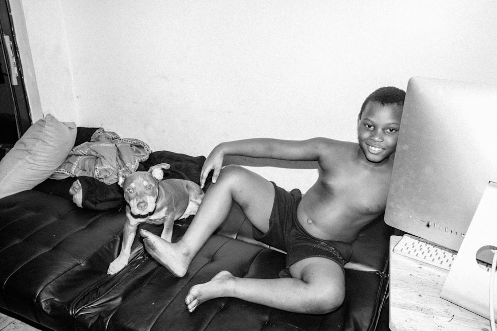 topless boy sitting on couch with dog on lap