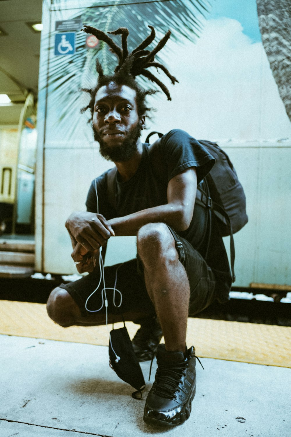 man in black t-shirt and black pants sitting on sidewalk during daytime