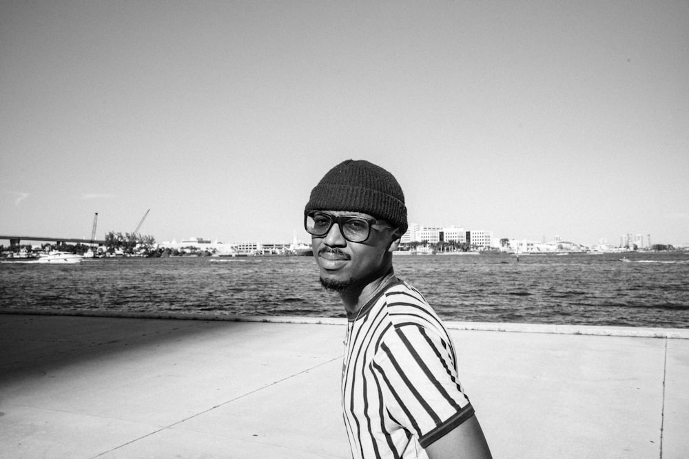 man in black and white striped shirt and black knit cap standing on gray concrete pavement