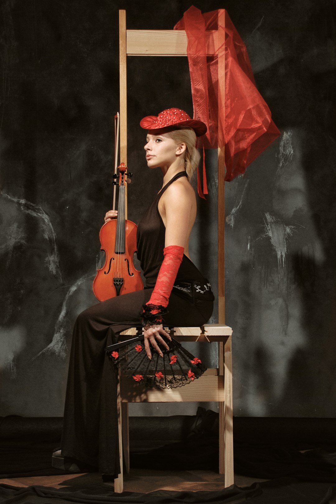 woman in black tank top and black pants sitting on chair playing brown acoustic guitar