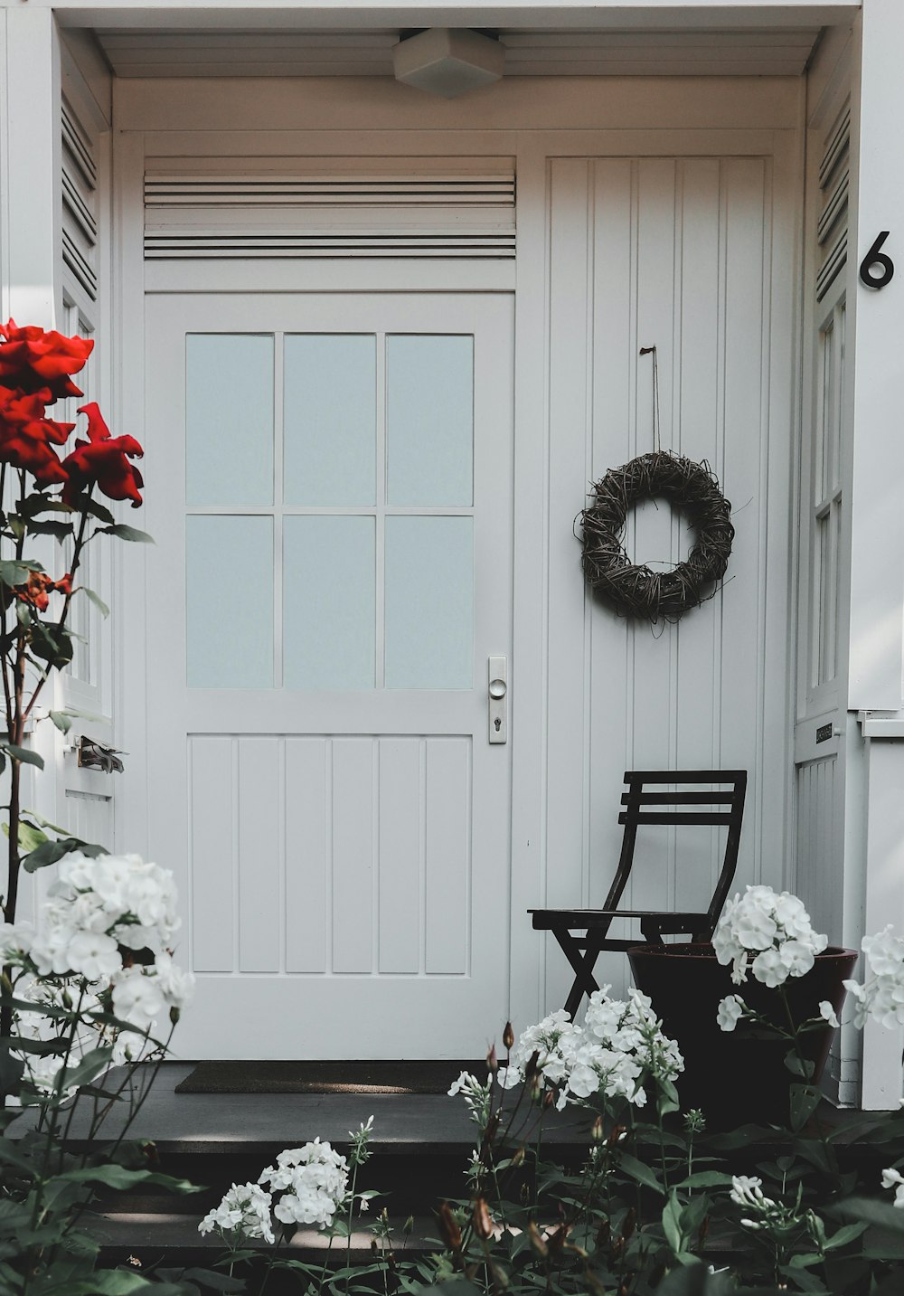 white and red flowers on white wooden door