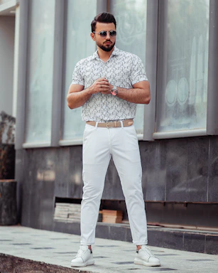 man in white pants and blue and white checkered button up shirt standing on gray concrete