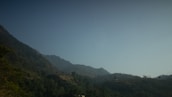 A peaceful mountain view in Himachal Pradesh with lush green hills and clear blue skies.