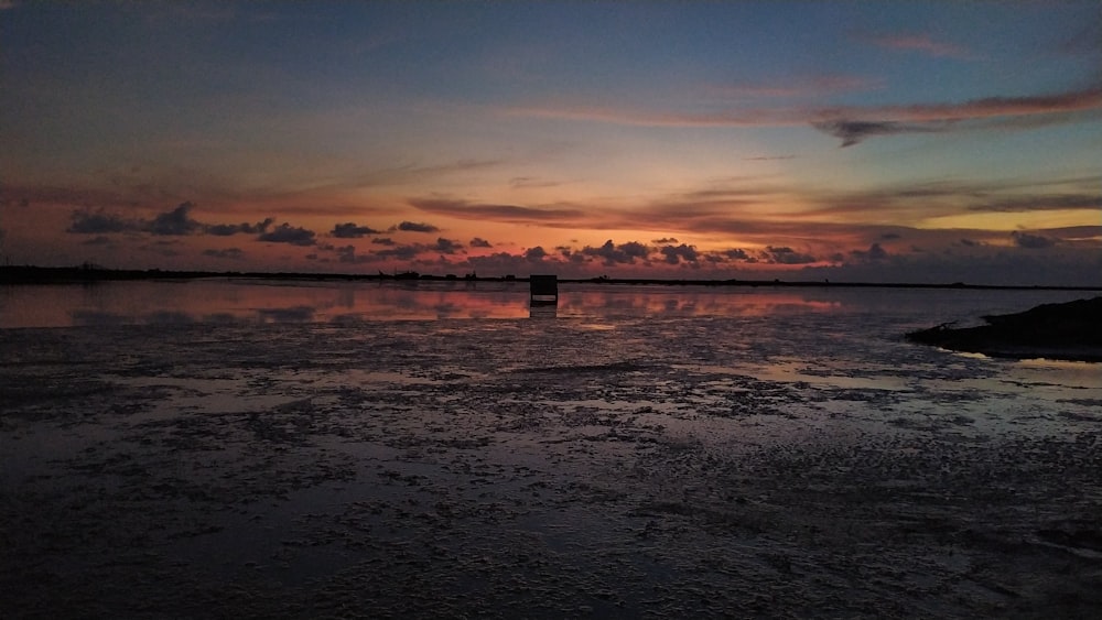 silhouette of person standing on sea dock during sunset