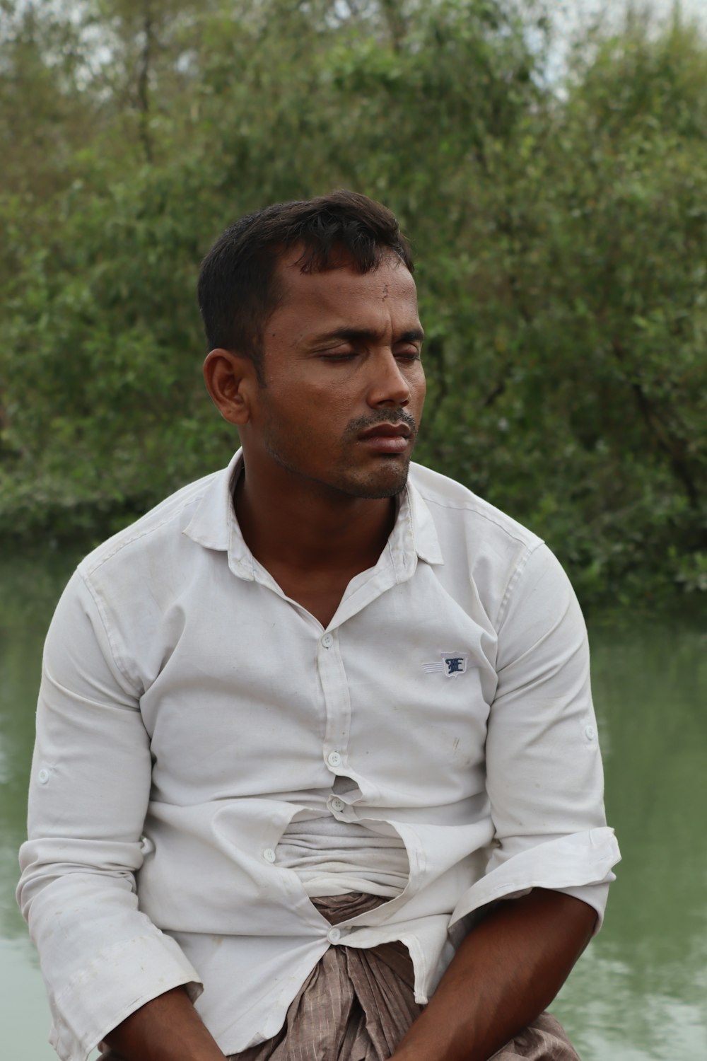 Mann im weißen Hemd tagsüber auf grünem Rasen stehend