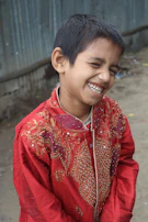 A young boy in a navy gold kurta pyjama smiling confidently against a festive backdrop.