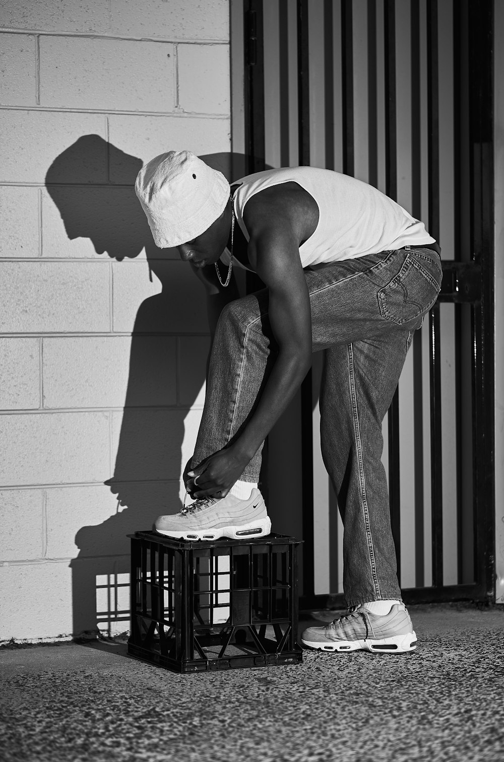 man in white t-shirt and blue denim jeans holding black plastic crate