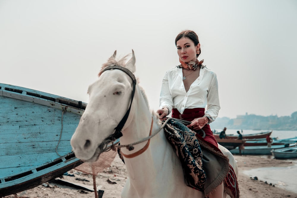 woman in white button up shirt riding white horse during daytime