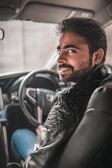 man in black leather jacket sitting on blue car seat
