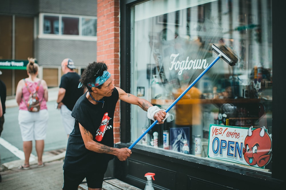 man in black t-shirt holding blue stick