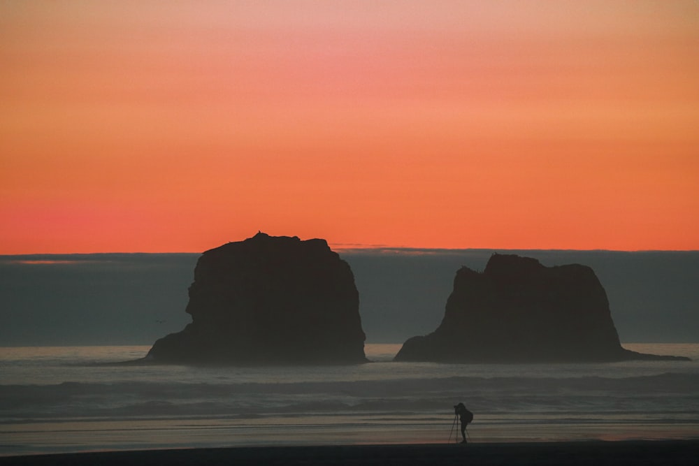 Silhouette von 2 Personen, die während des Sonnenuntergangs am Strand spazieren gehen