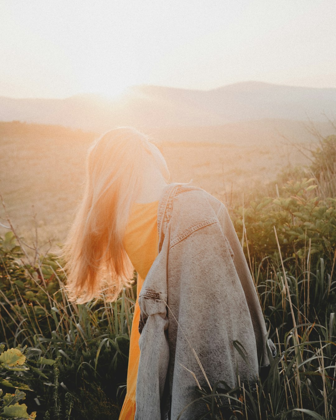 woman in gray jacket standing on green grass field during daytime