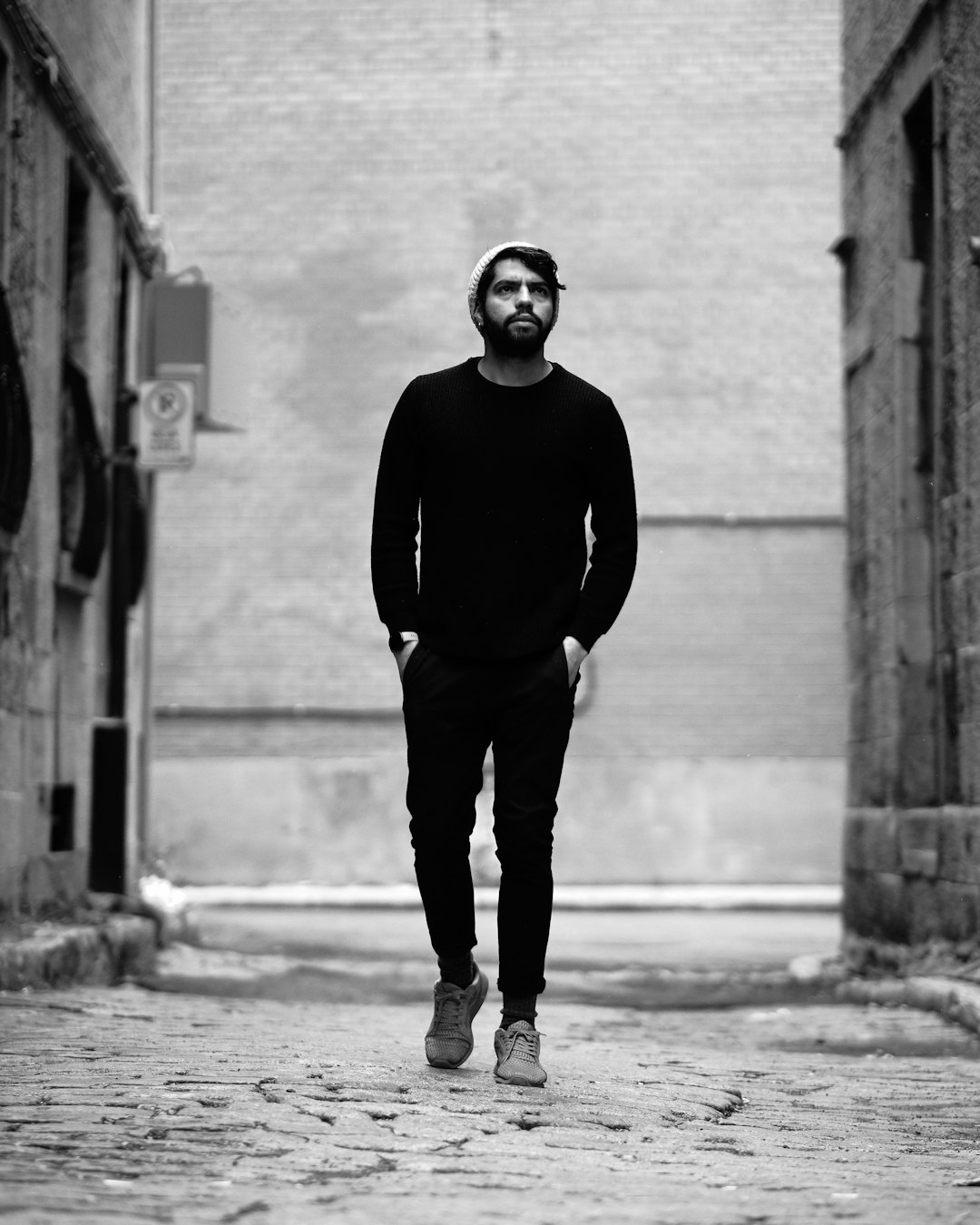 man in black long sleeve shirt and black pants standing on sidewalk during daytime