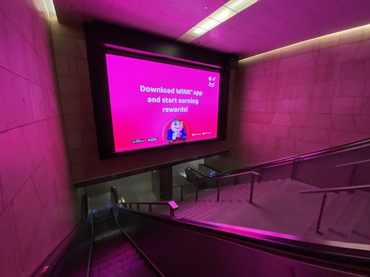 an escalator with a large screen on the wall