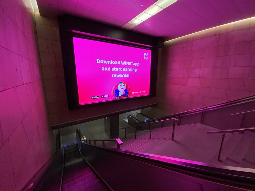 an escalator with a large screen on the wall
