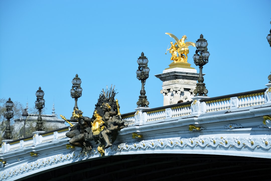 gold and black statue on top of white concrete bridge