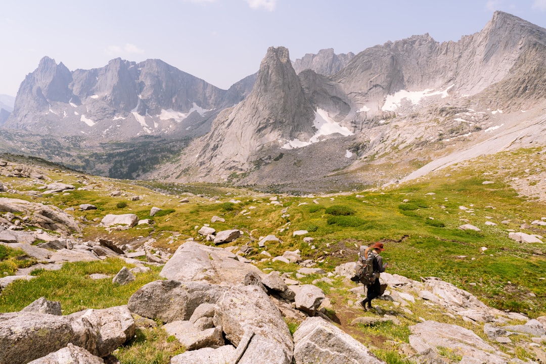 person in black jacket sitting on rock near gray rocky mountain during daytime