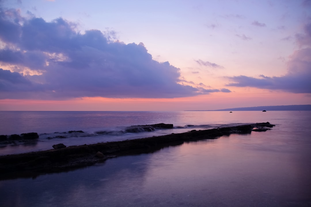 body of water under cloudy sky during sunset