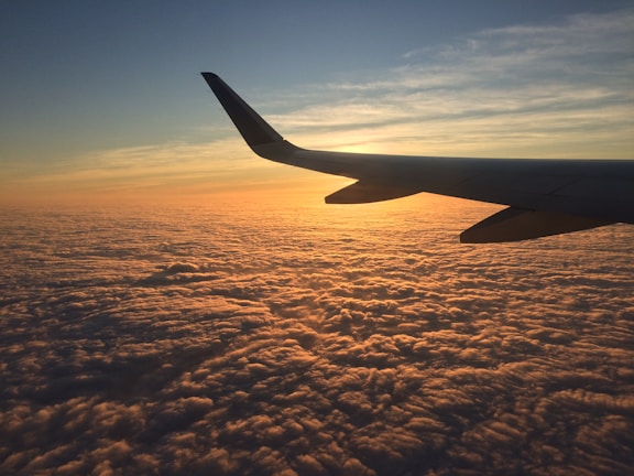 A sleek aircraft soaring above the clouds during a sunset flight.