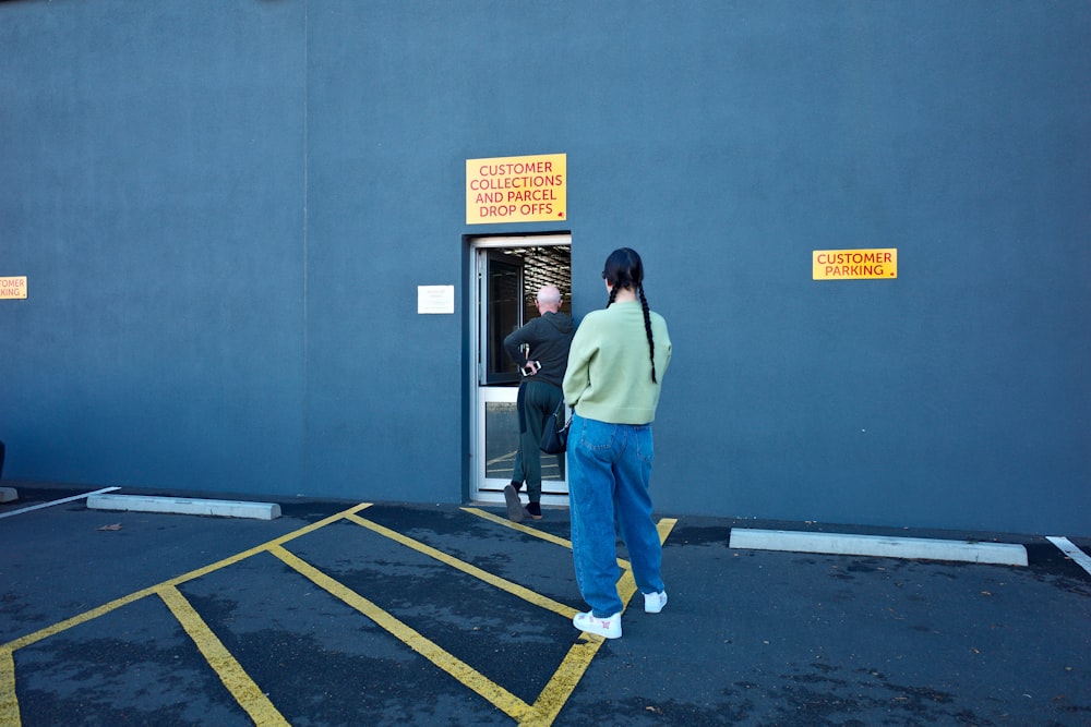 woman in blue denim jeans standing near blue wall