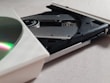 A close-up view of an open CD/DVD drive with a partially visible disc. The drive's mechanism, including the laser lens and spindle, is clearly visible. The background is a plain light-colored surface.
