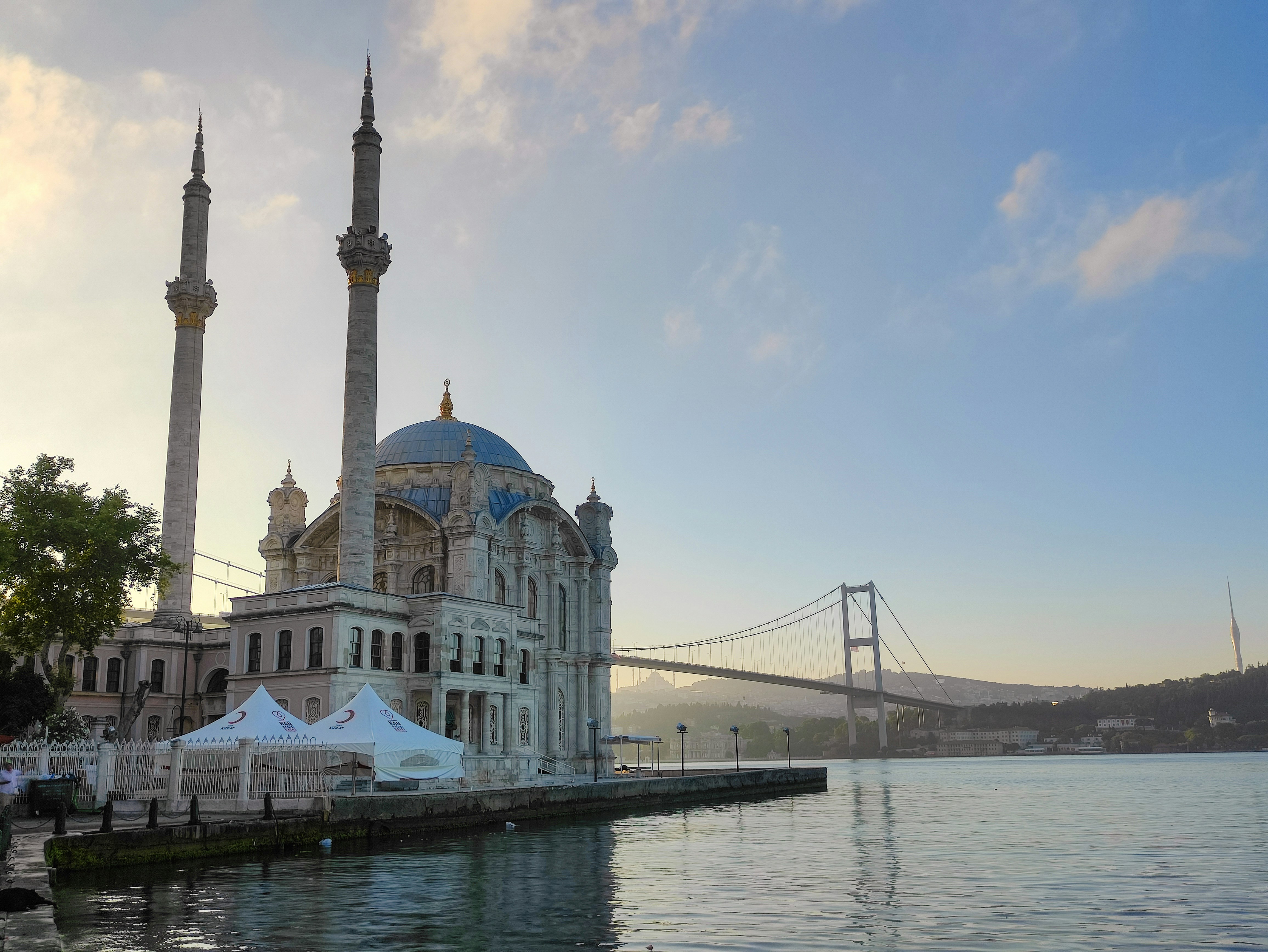 Istanbul Blue Mosque at dusk with minarets illuminated against deep blue sky, calm Bosphorus in background