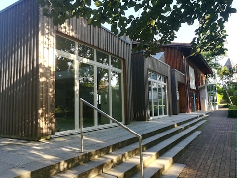 A modern glass-and-steel school building surrounded by greenery.