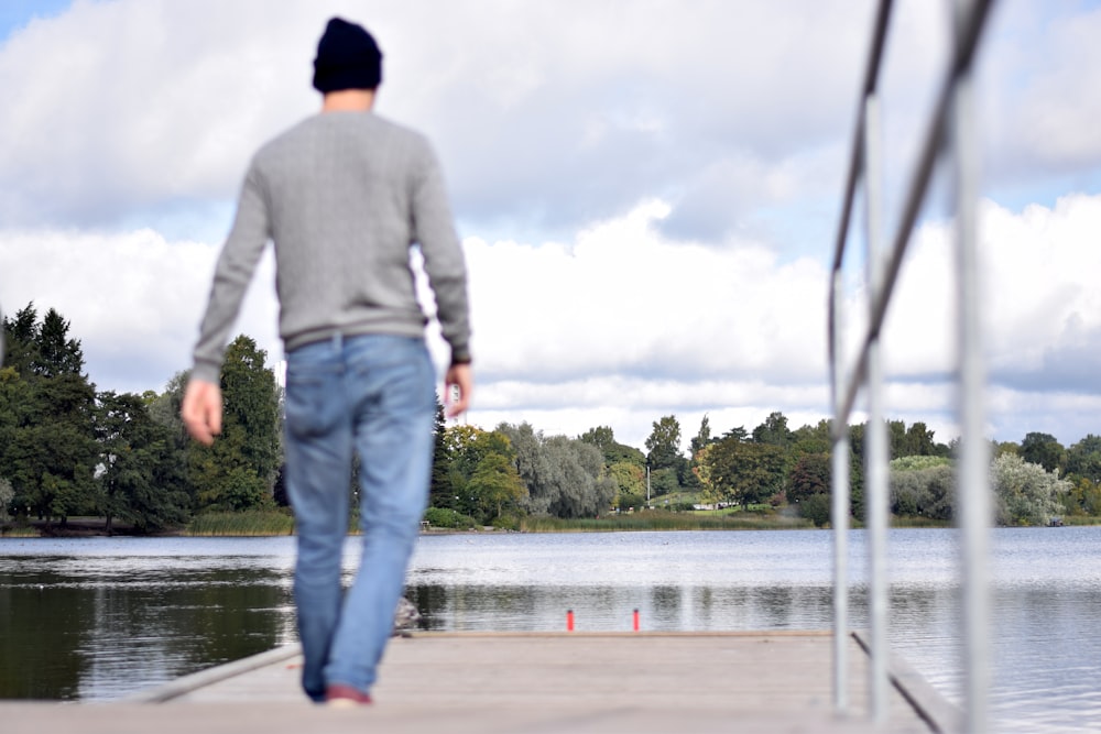 man in white long sleeve shirt and blue denim jeans standing on gray concrete floor during