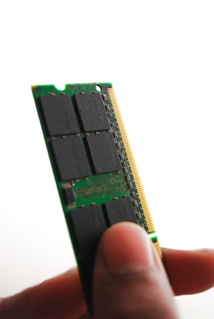 A close-up of a memory module being installed into a laptop, emphasizing precision and care.