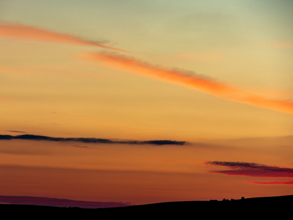 silhouette of mountain under orange and blue sky