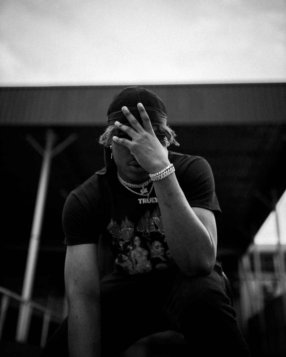 grayscale photo of man in crew neck t-shirt covering face with hands