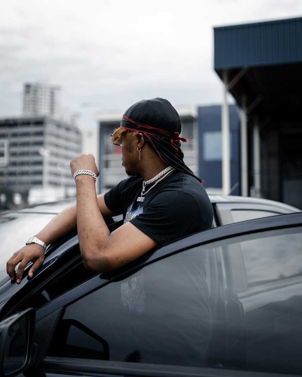 man in black shirt leaning on car