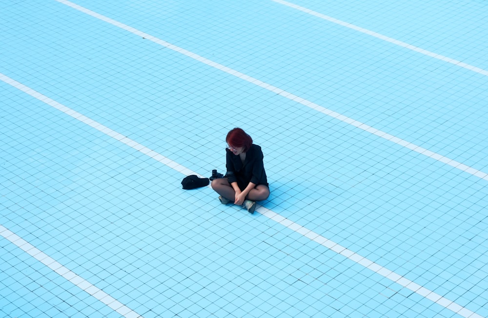 man in black t-shirt and black pants sitting on white and blue floor