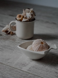 Close-up of a natural tooth powder jar with sea urchin shells around on a wooden table.