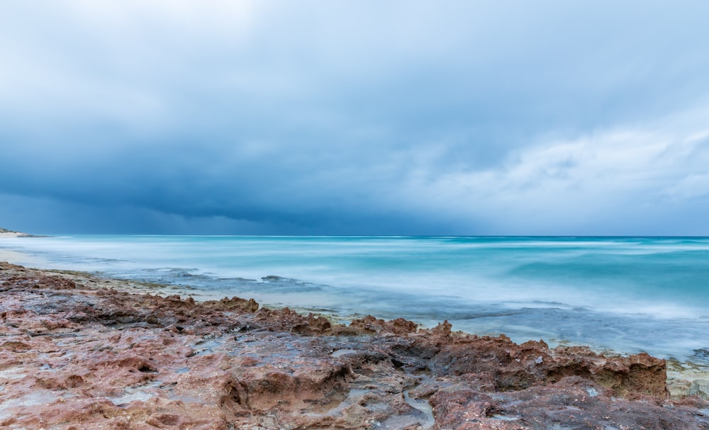 brown rocky shore under gray cloudy sky