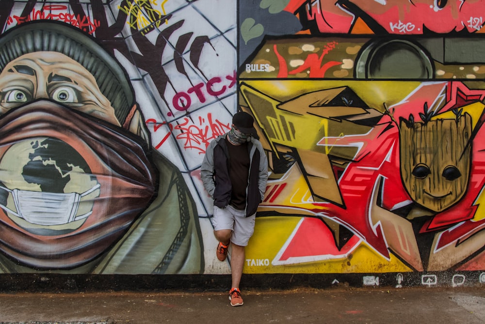 Frau in schwarzer Jacke und gelben Shorts geht an der Graffiti-Wand entlang