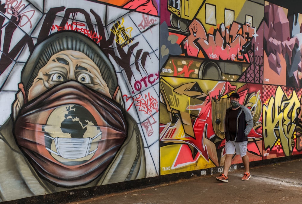 woman in white t-shirt and blue denim jeans standing beside graffiti wall