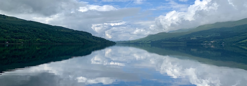 body of water near mountain under blue sky during daytime