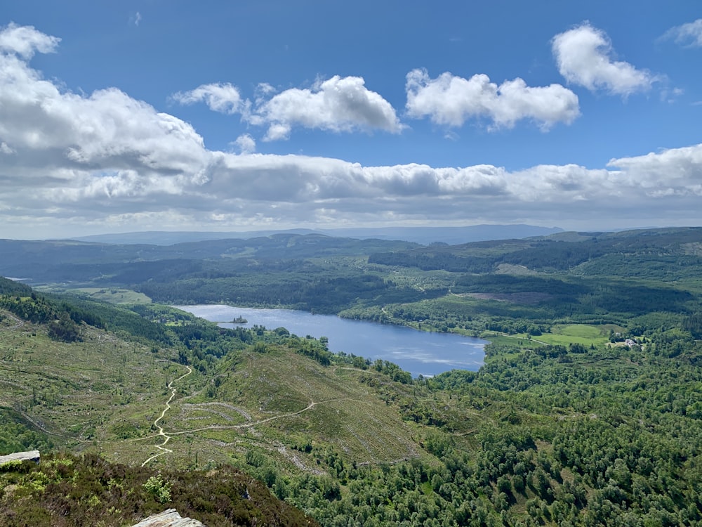 green mountains near body of water under blue sky during daytime