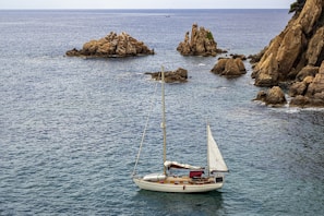 a sailboat in the ocean with rocks in the background