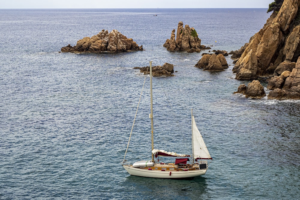 Una barca a vela nell'oceano con rocce sullo sfondo